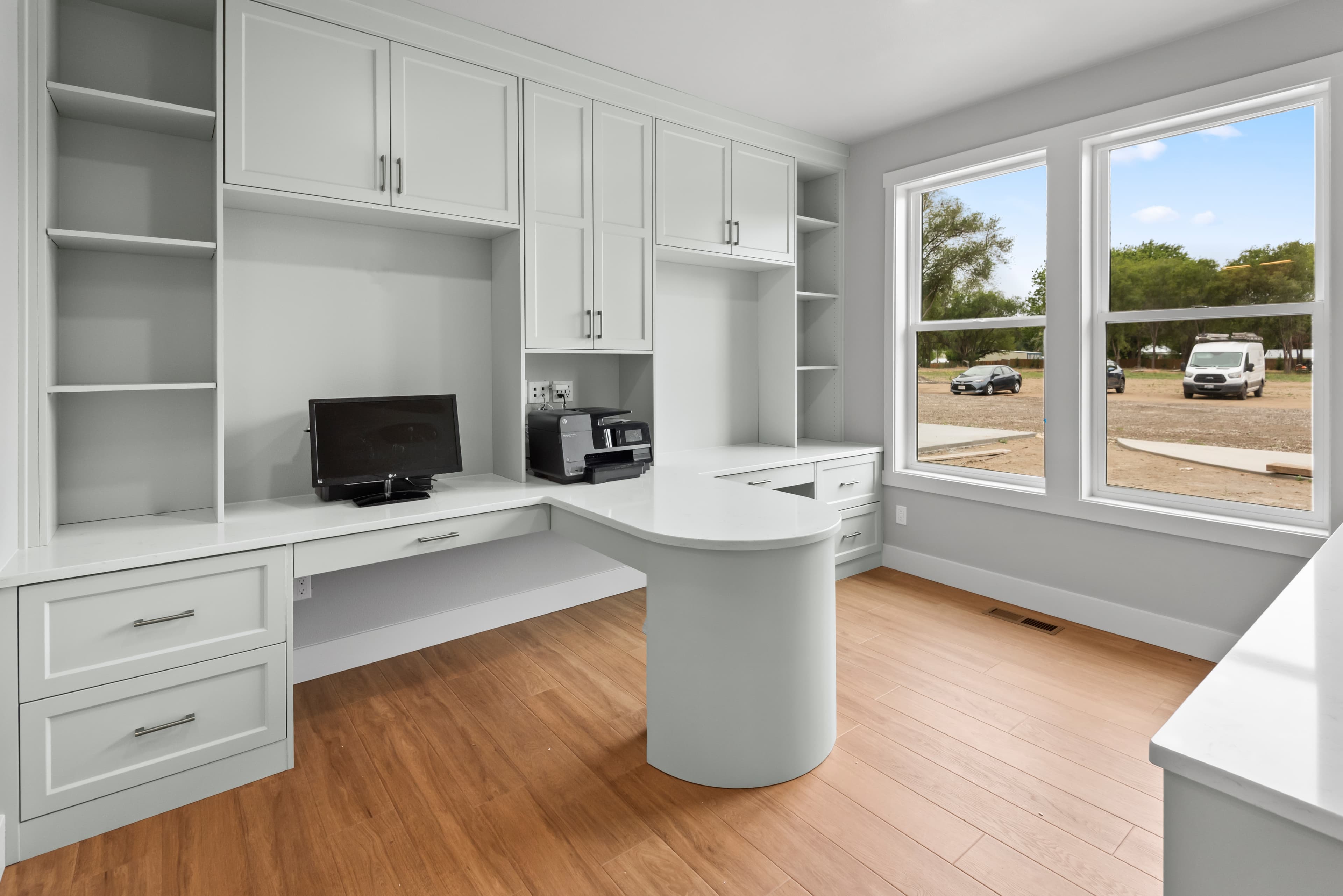 Home office built-in with curved desk and overhead cabinets