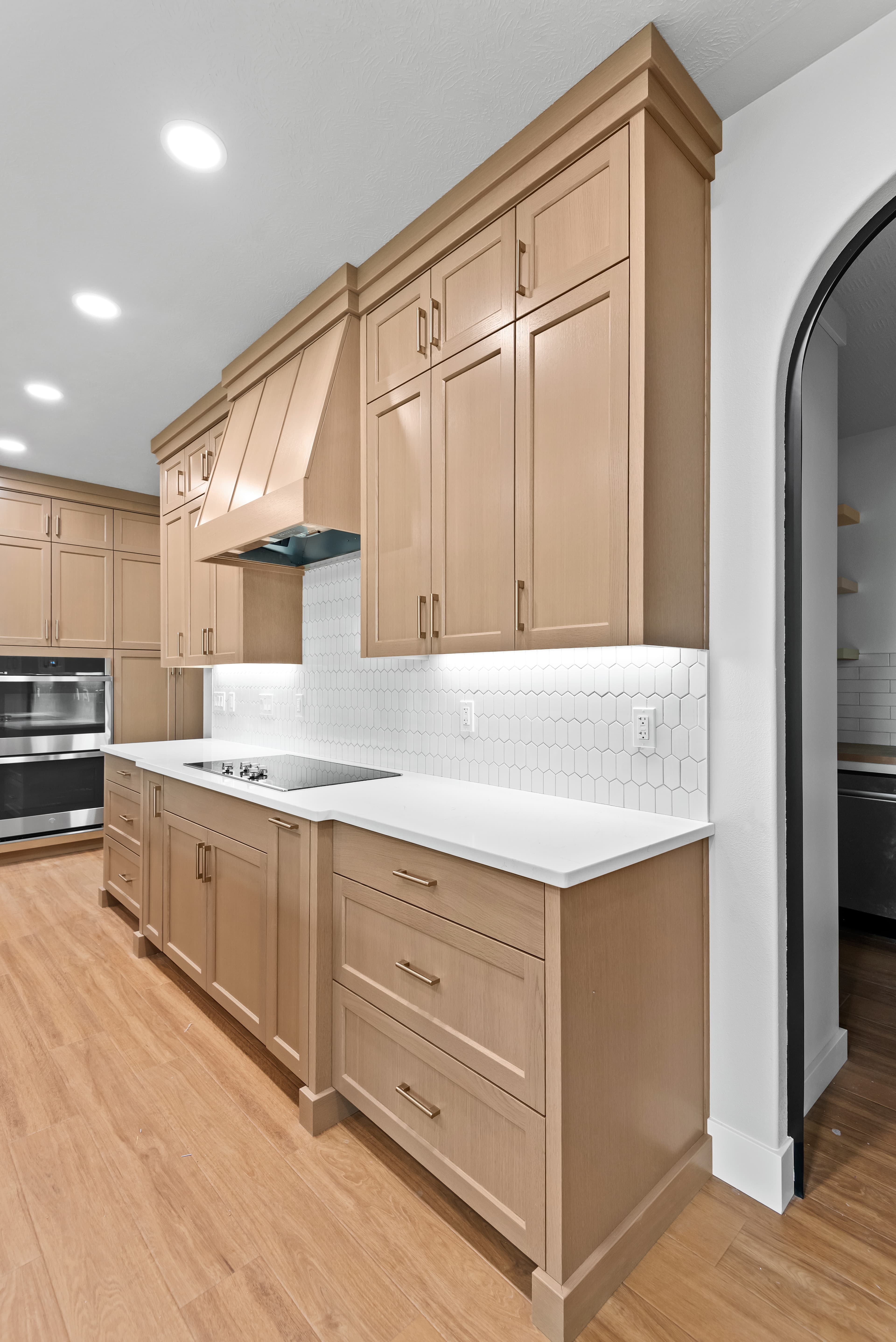 Warm wood kitchen with range hood and archway