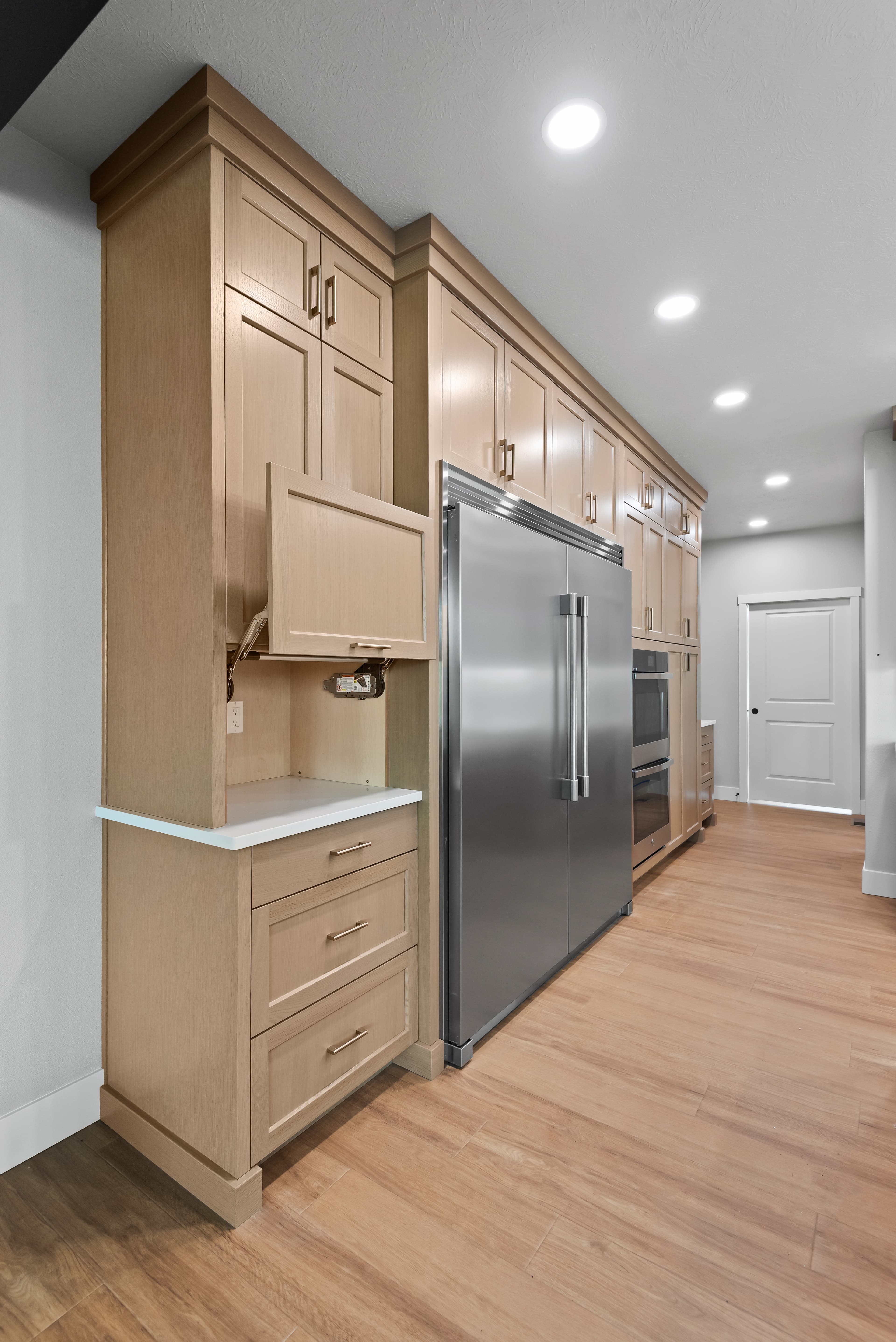 Built-in pantry cabinet beside a paneled refrigerator