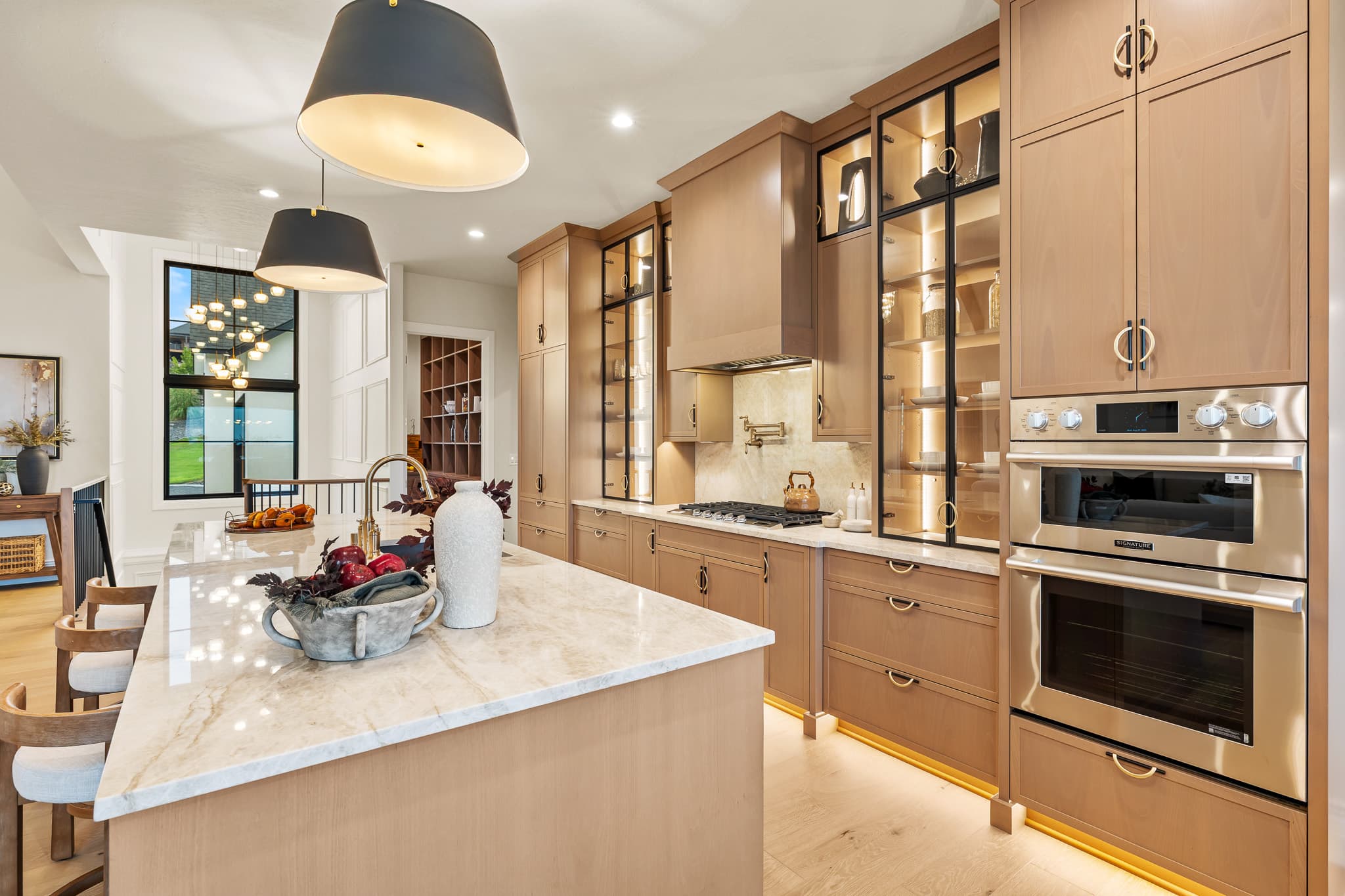 Warm wood kitchen with glass-front upper cabinets and pendant lighting