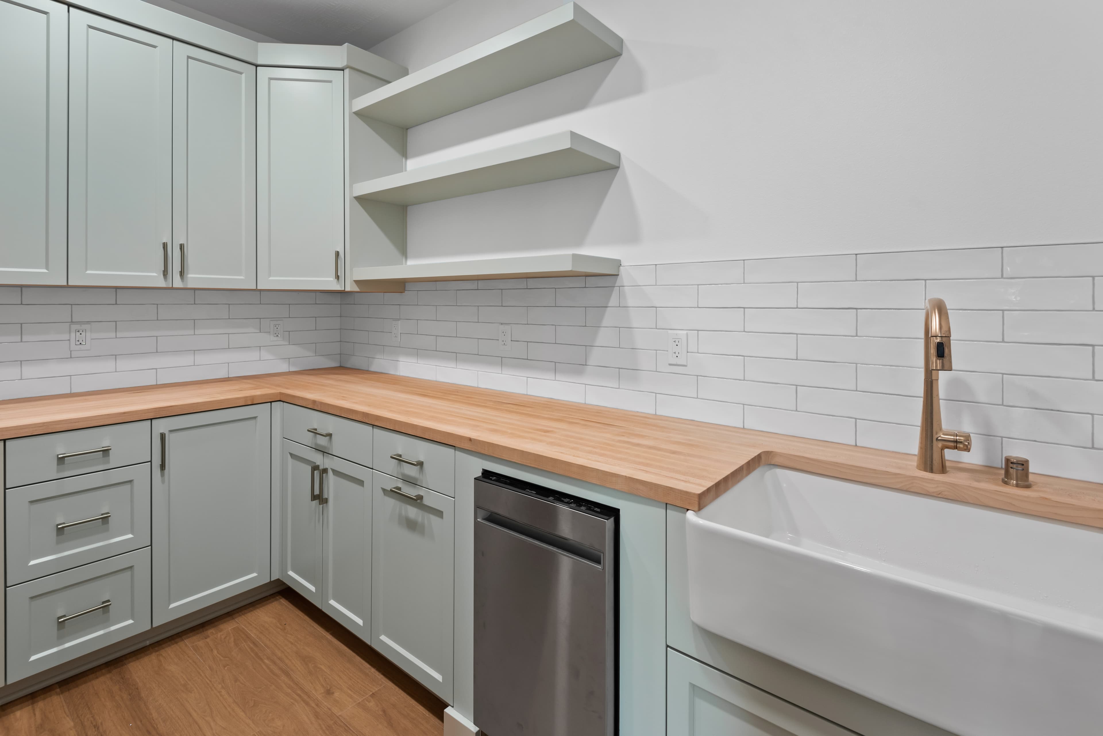 Light pantry with farmhouse sink and floating shelves